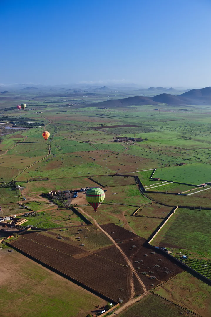 Uitzicht vanuit de mand van een luchtballon over de uitgestrekte vlaktes rond Marrakech